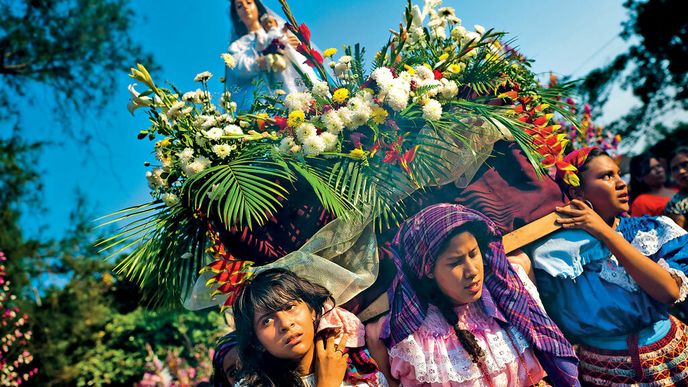 Oblečeny v tradičních šatech nesou ženy sochu Panny Marie na dřevěném trůnu městem.