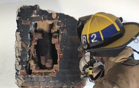 Po vybourání stěny se hasičům naskytl pohled na nohy zloděje.