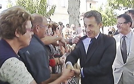 Sarkozy si potřásá rukou s lidmi.