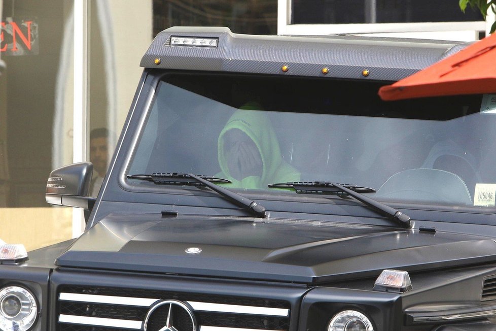 Justin Bieber sedí v autě a schovává si hlavu v dlaních.