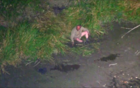 Muž seděl v bahně na okraji rybníka.