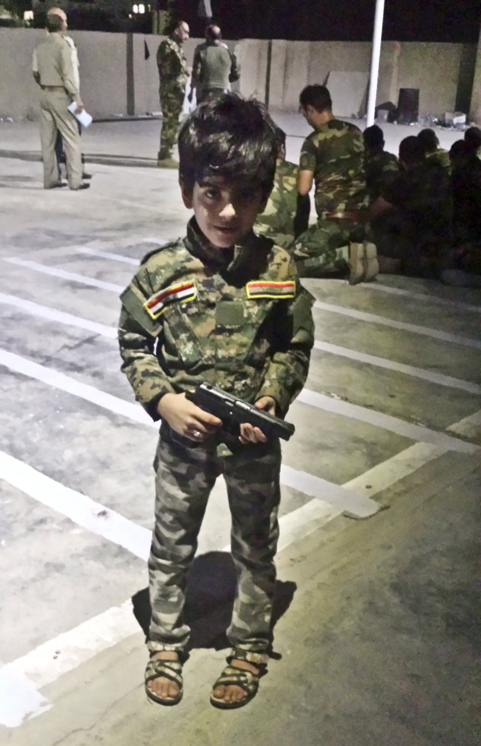 Pětiletý syn instruktora šíitských milicí Abdulhakim v uniformě s pistolí svého táty.