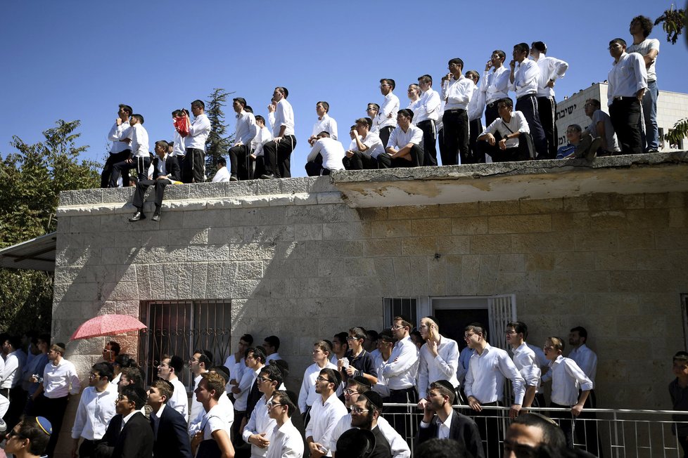 Mladí ortodoxní Židé sledují zpovzdálí pohřeb Šimona Perese