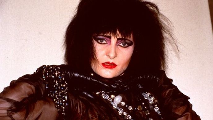 Gothic punková Siouxsie Sioux září ve zlatém overalu a na pódiu vykopává nohy do výšky