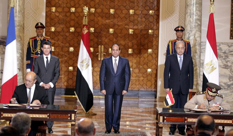 Egyptský prezident Abdal Fattáh Sísí (uprostřed), doprovázený francouzským premiérem Manuelem Vallsem (vlevo) a egyptským premiérem Šarífem Ismáílem přihlížejí v sobotu podpisu bojové dohody mezi francouzským ministrem obrany a jeho egyptským protějškem.