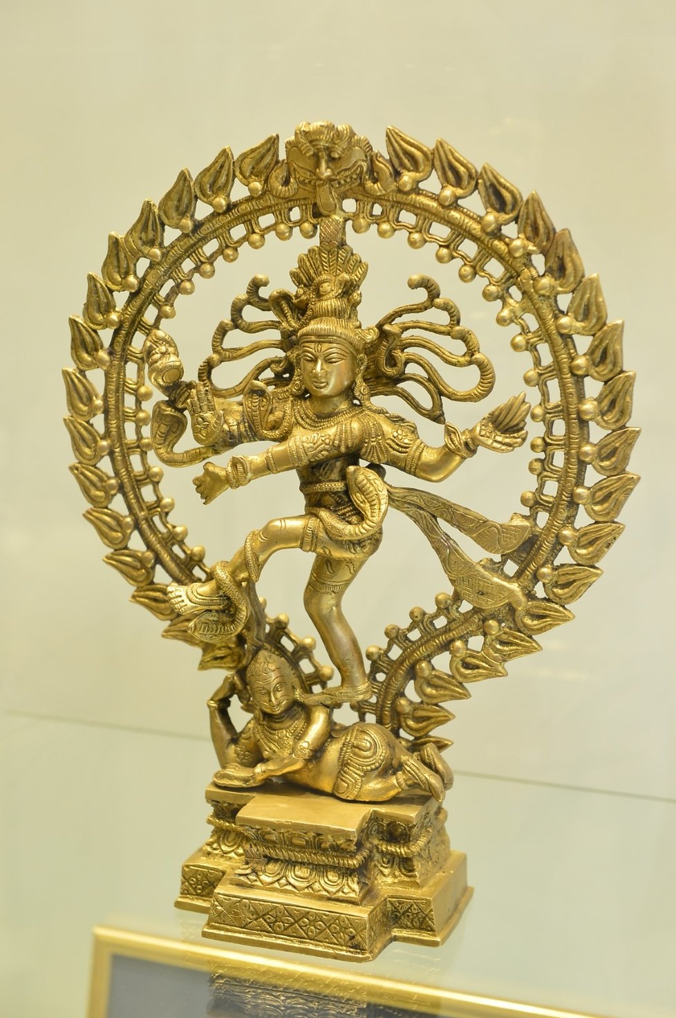 Hinduistický bůh Šiva zobrazený jako Natarádža, čili král tance, v kruhu a jednou nohou stojící na démonovi Mudžalakovi. Tanec vyjadřuje různě se proměňující svět.  Dar z návštěvy vývojového centra Škoda Volkswagen v indické Puné.