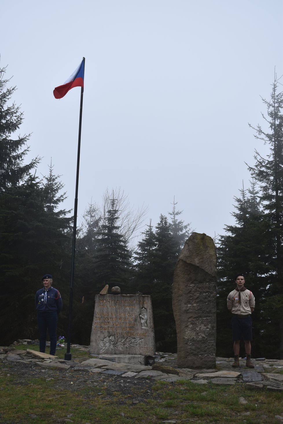 Skauti drží hlídku u vztyčené státní vlajky u památníku poblíž mohyly.