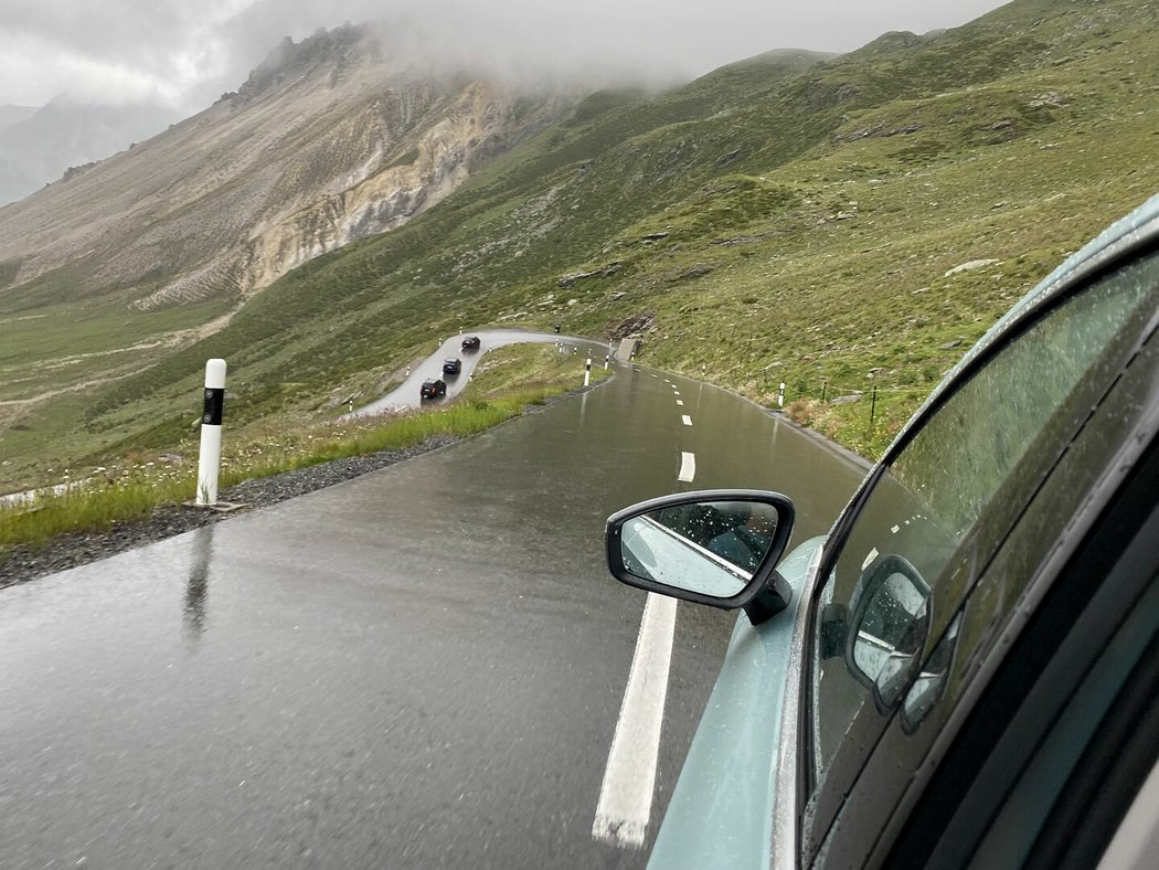 První kilometry ve Švýcarsku, to jsou mokré serpentiny a žel také oblačnost zakrývající jinak majestátní hory.