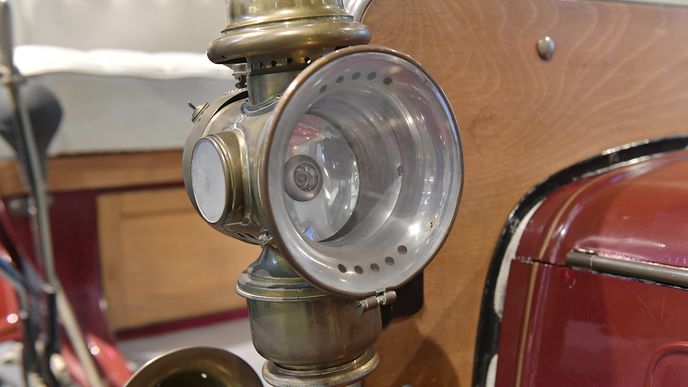 V případě exponátu Laurin & Klement Vouiturette A jsou světlomety stavěny na úroveň pouhého doplňku, příplatkového prvku. V roce 1906, ze kterého vůz pochází, totiž nebyly povinné. Jedná se o vůbec první typ svícení v autě. Lampy používaly acetylen, který uvnitř hořel. Za plamenem se nachází zrcadlo, které paprsky rozptyluje před vůz. Jak prosté a ... oslňující.