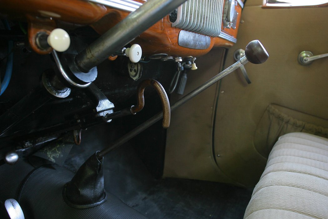 Dlouhou řadicí páku doplňuje táhlo ruční brzdy zakončené tvarem důchodcovské hole. Na zabrzděná kola neupozorňuje žádná kontrolka, což si škodovky s motorem vzadu ponechaly až do roku 1990.