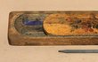 Dřevěný malovaný penál s břidlicovým pisátkem je ve sbírce Regionálního muzea v Teplicích