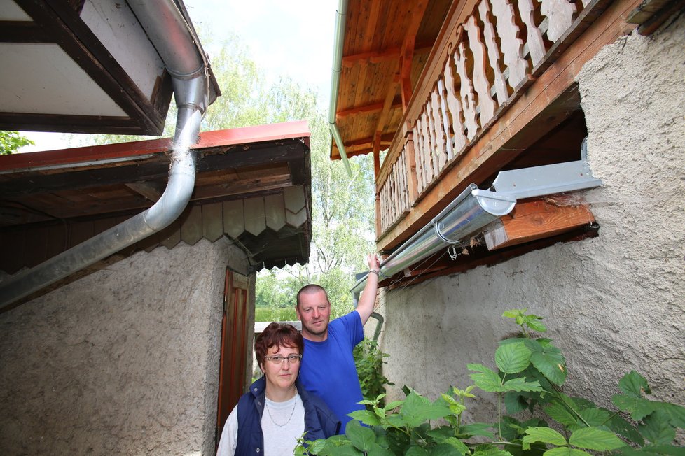 Plechová střecha kůlny viditelně přesahuje na pozemek sousedů. Okap si museli namontovat sami, aby dešťová voda netekla k nim na záhonky.