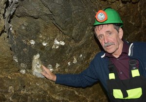 Jaroslav Dvořák ukazuje krystaly slídy položené ve výklenku těžební komory.