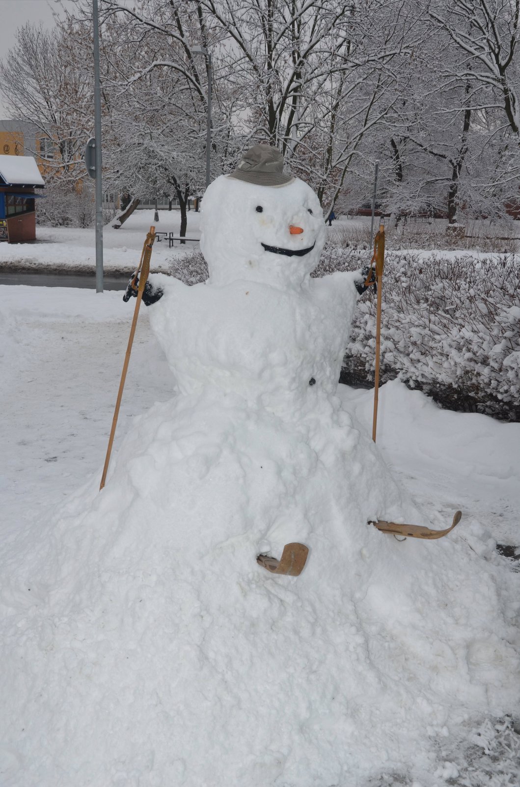 Sněhový muž-lyžař u obchodu se sportovními potřebami.