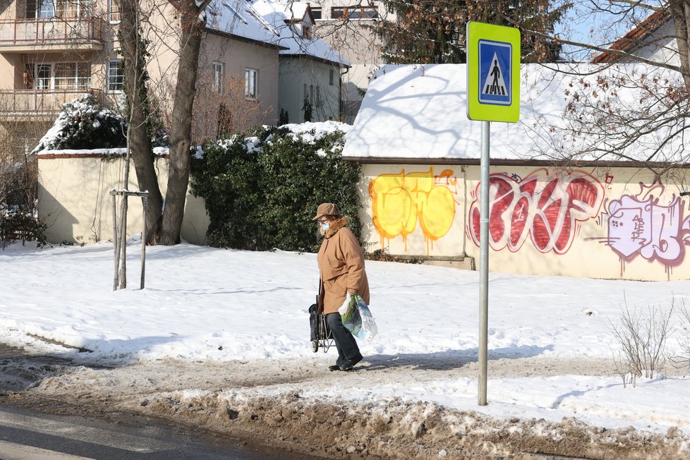 Únor 2021: Zasněžená Praha dělá problémy chodcům. 1 200 metačů se sice o chodníky stará, kvůli sněhu a námraze však kloužou dál.