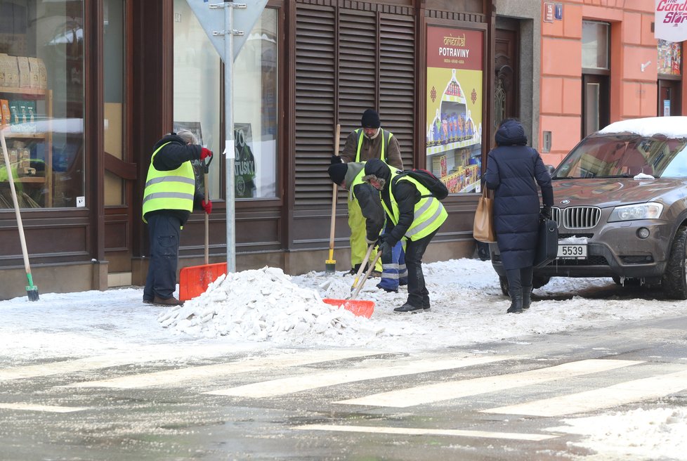 Únor 2021: Zasněžená Praha dělá problémy chodcům. 1 200 metačů se sice o chodníky stará, kvůli sněhu a námraze však kloužou dál.