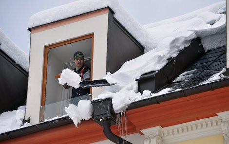 Muž shazuje sníh ze střechy v Jeseníku, kde během minulého týdne vydatné sněžení vedlo až k vyhlášení stavu kalamity.