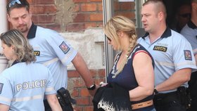 Policisté odvádí Janu Nagyovou z policejního oddělení a povezou ji k soudu