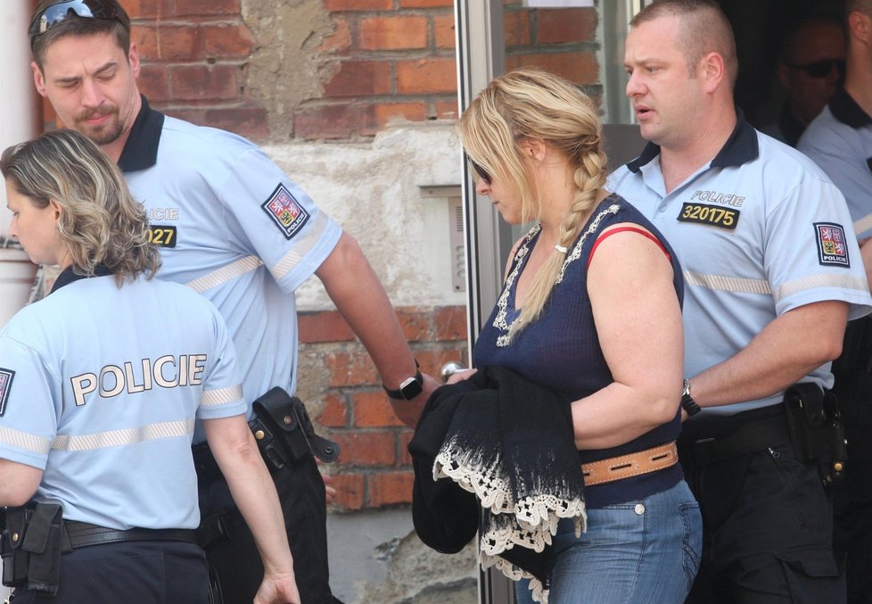 Policisté odvádí Janu Nagyovou z policejního oddělení a povezou ji k soudu