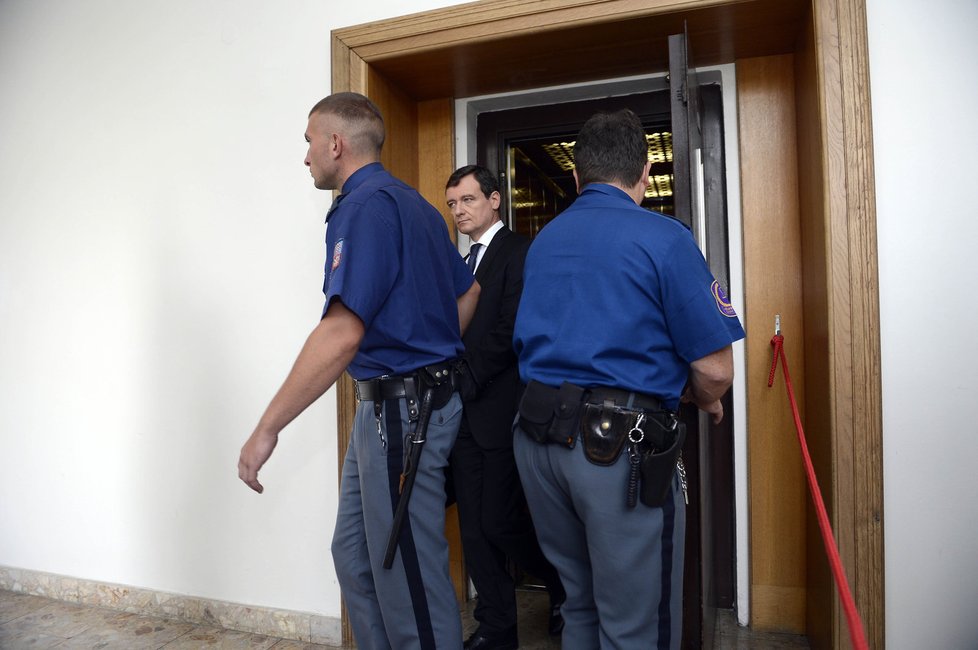 Již klasický obrázek z procesu s Rathem: Davida Ratha vyvádějí z výtahu a odvádí do soudní síně