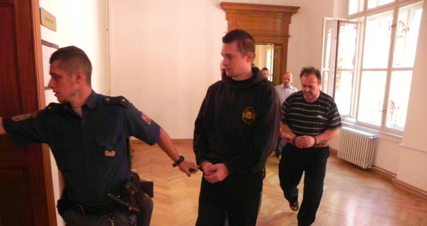 Trojici obžalovaných přivádí eskorta do soudní síně. V popředí Josef D. mladší, za ním jeho otec.