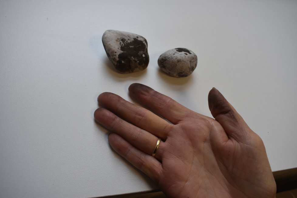 Okrasné kamenivo zasažené sazemi. Marie Vavříková ukazuje jak stále špiní.