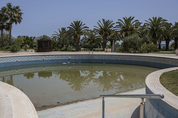 V bazénu stojí zelená voda a okolí zeje prázdnotou.