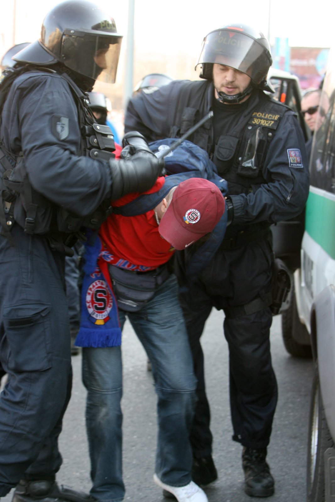Policisté zpracovávají jednoho ze zadržených.