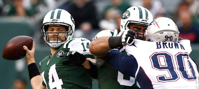 Quarterback Jets Ryan Fitzpatrick (vlevo) se snaží rozehrát v utkání proti Patriots