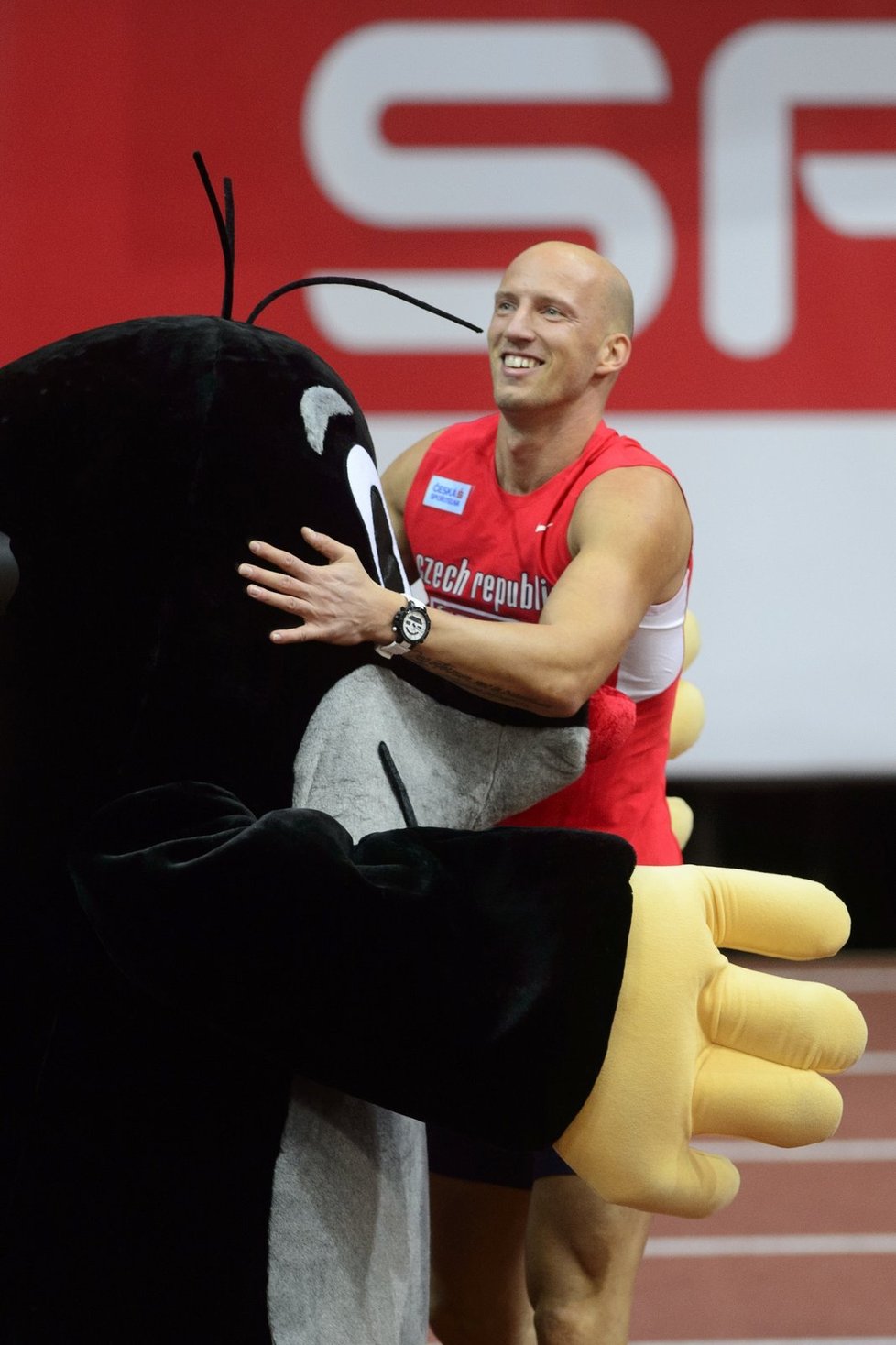 Petr Svoboda se objímá s maskotem pražského šampionátu po svém úspěšném rozběhu na 60 metrů překážek...