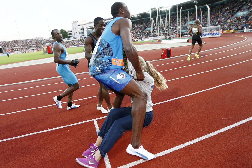 Usain Bolt chytá dívku s kyticí pro vítěze, kterou srazil po doběhu stovky v Oslo