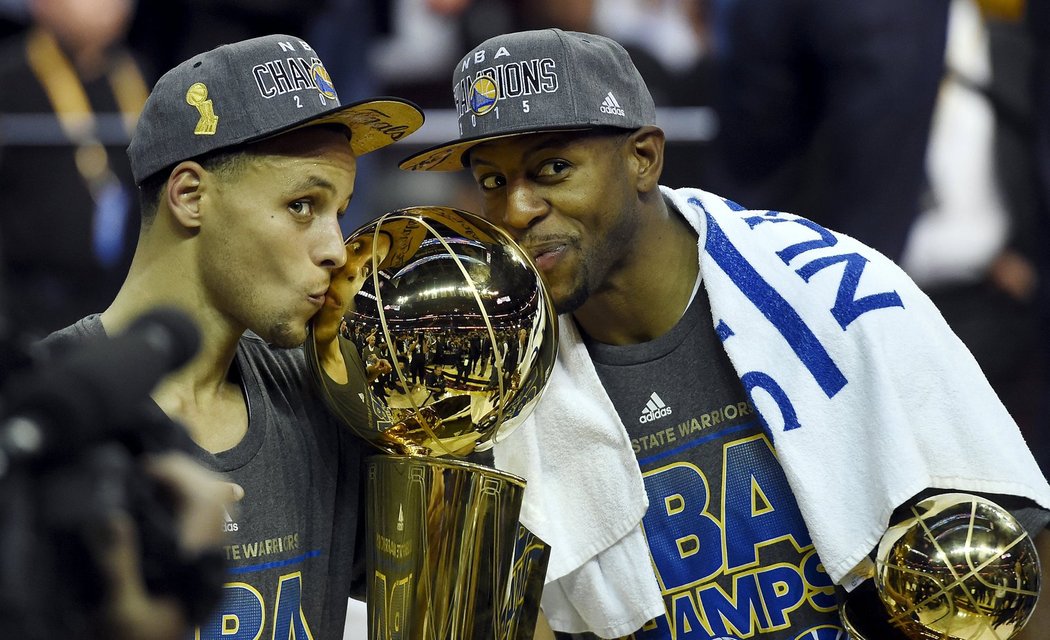 Stephen Curry a Andre Iguodala pózují s vítěznou trofejí.