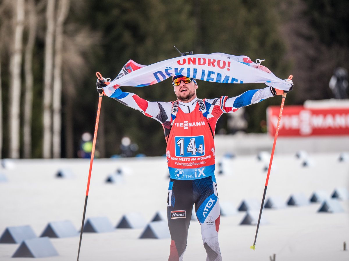 Michal Krčmář dojíždí do cíle smíšené štafety v Novém Městě s vlajkou s poděkováním Ondřeji Moravcovi