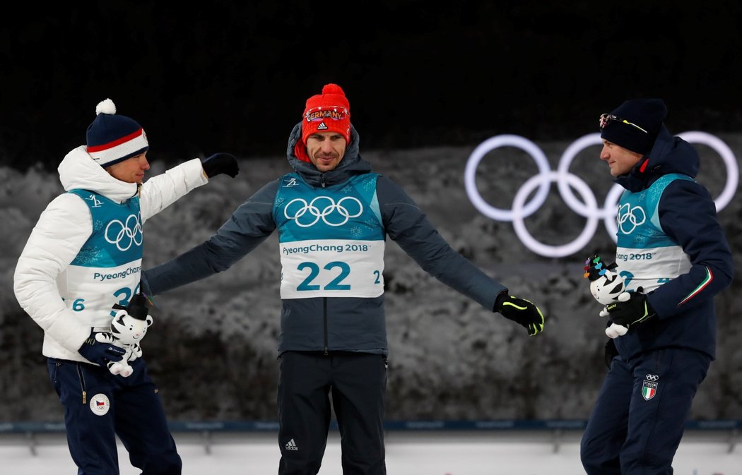 Stupně vítězů po sprintu biatlonistů na olympiádě v Pchjongčchangu. Vlevo se raduje stříbrný Michal Krčmář.