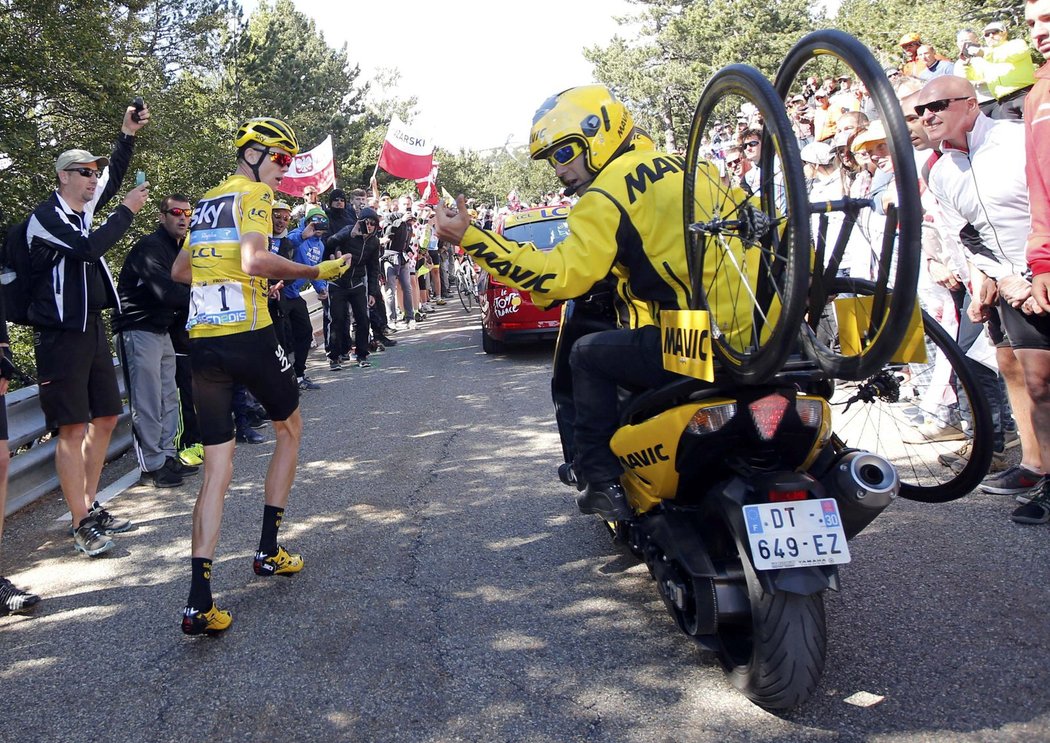 Lídr Tour de France Chris Froome čeká, až se k němu po kolizi v závěru 12. etapy dostane náhradní kolo