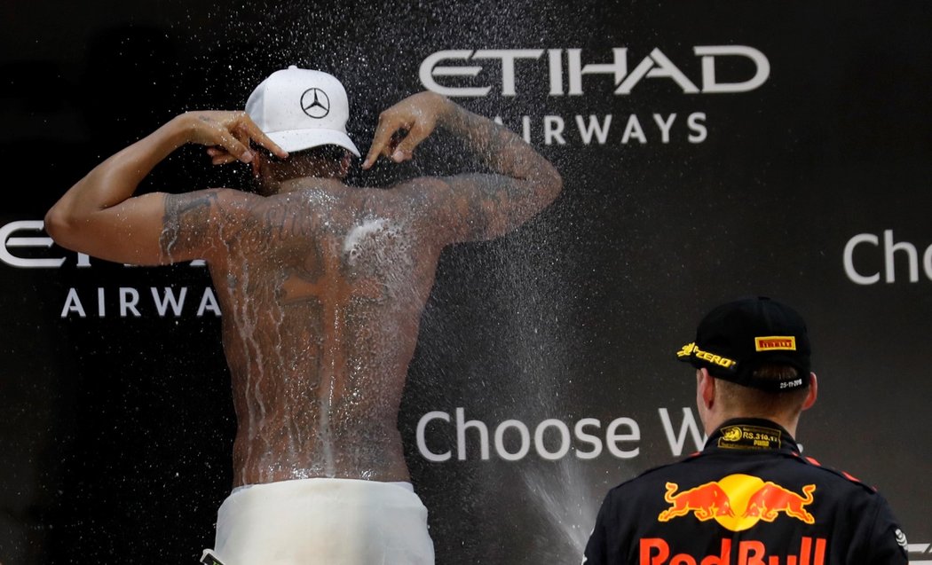 Lewis Hamilton se nechá kropit šampaňským od Maxe Verstappena po posledním zápase sezony
