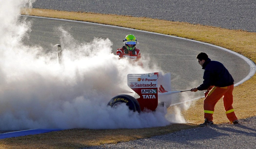Personál na okruhu ve Valencii se snaží uhasit hořící Ferrari Felipeho Massy