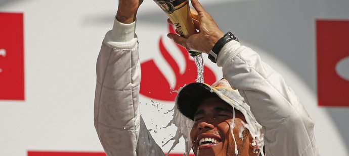 Lewis Hamilton se polévá šampaňském po výhře ve VC Británie