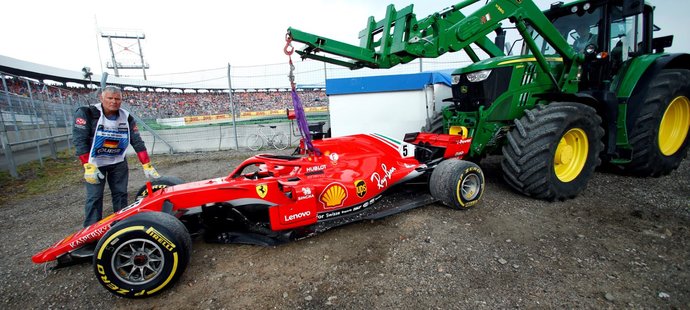 Traťový personál odstraňuje nabouraný monopost Sebastiana Vettela