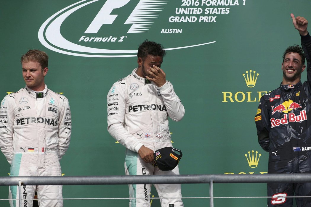 Lewis Hamilton si protírá oči na stupních vítězů po Velké ceně USA, ve které porazil Nica Rosberga (vlevo) a udržel teoretickou šanci na zisk titulu