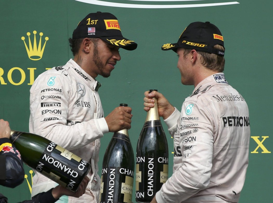 Lewis Hamilton (vlevo) a Nico Rosberg si připíjejí šampaňským po americkém triumfu  britského pilota