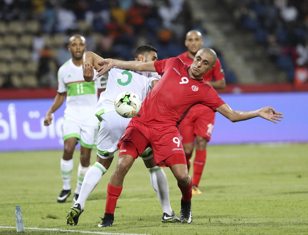 Ahmed Akaichi z Tuniska si hlídá míč před obránci Alžírska
