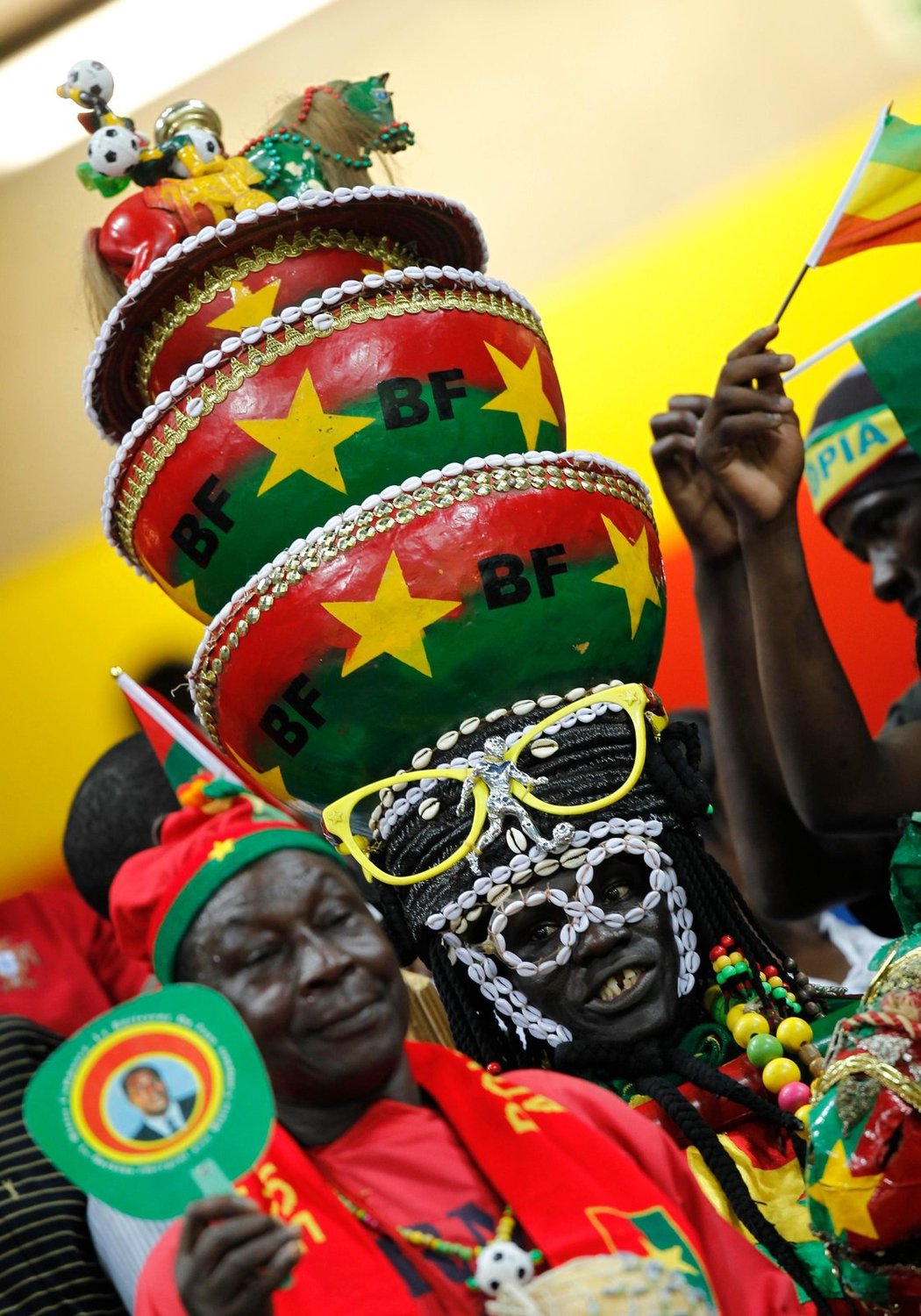 Fanoušci Burkiny Faso a jejich zajímavé módní kreace na africkém fotbalovém mistrovství. Zajímavé modely ale předvádějí i fanoušci dalších mužstev. Fandí se s trávou na hlavě, v paruce i s obrázkem Nelsona Mandely