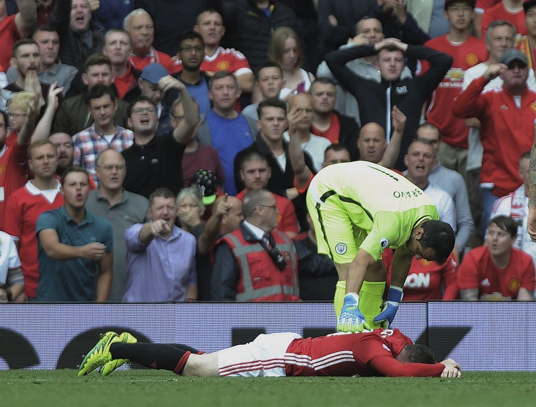 Gólman Manchesteru City se sklání nad kapitánem United Waynem Rooneyem během derby v Premier League.
