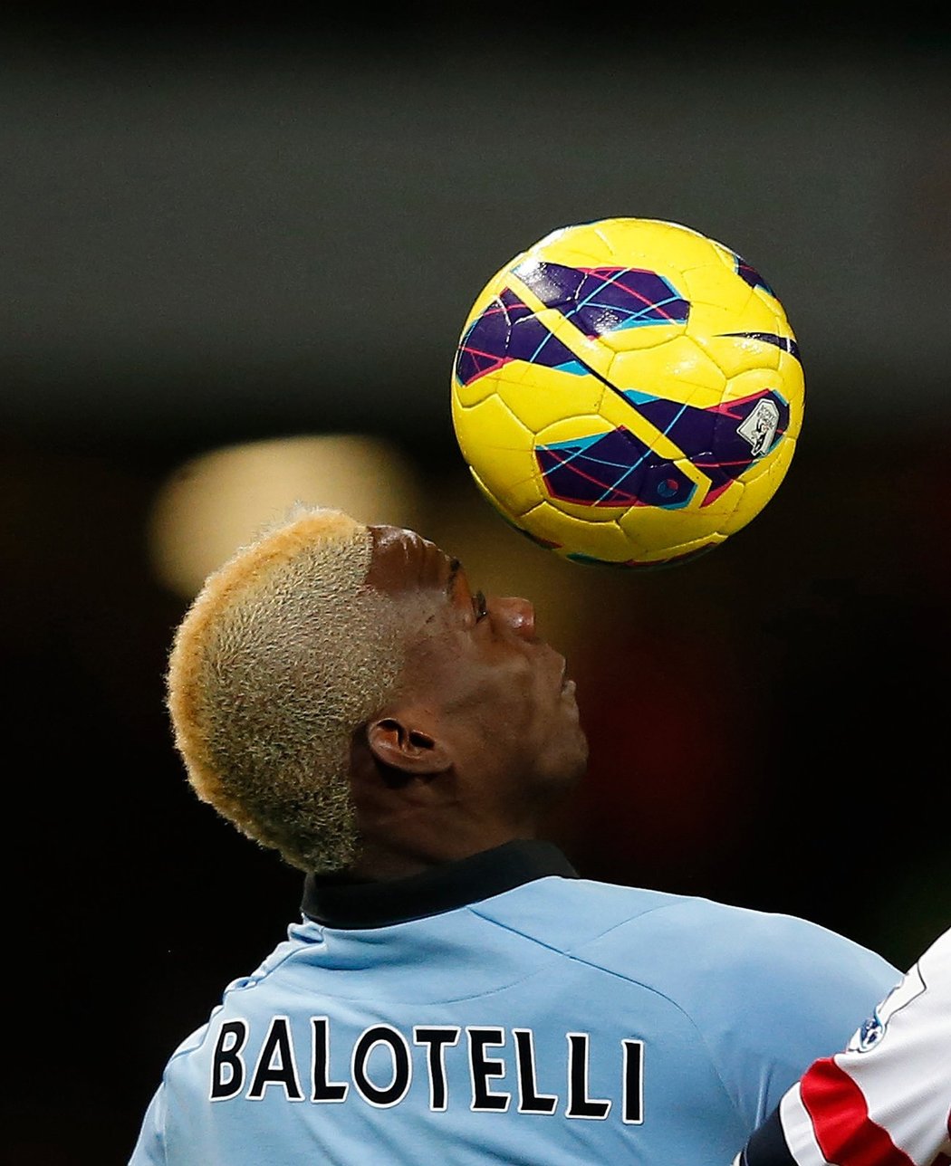 Mario Balotelli hlavičkuje se svou blonďatou hřívou v zápase proti Arsenalu