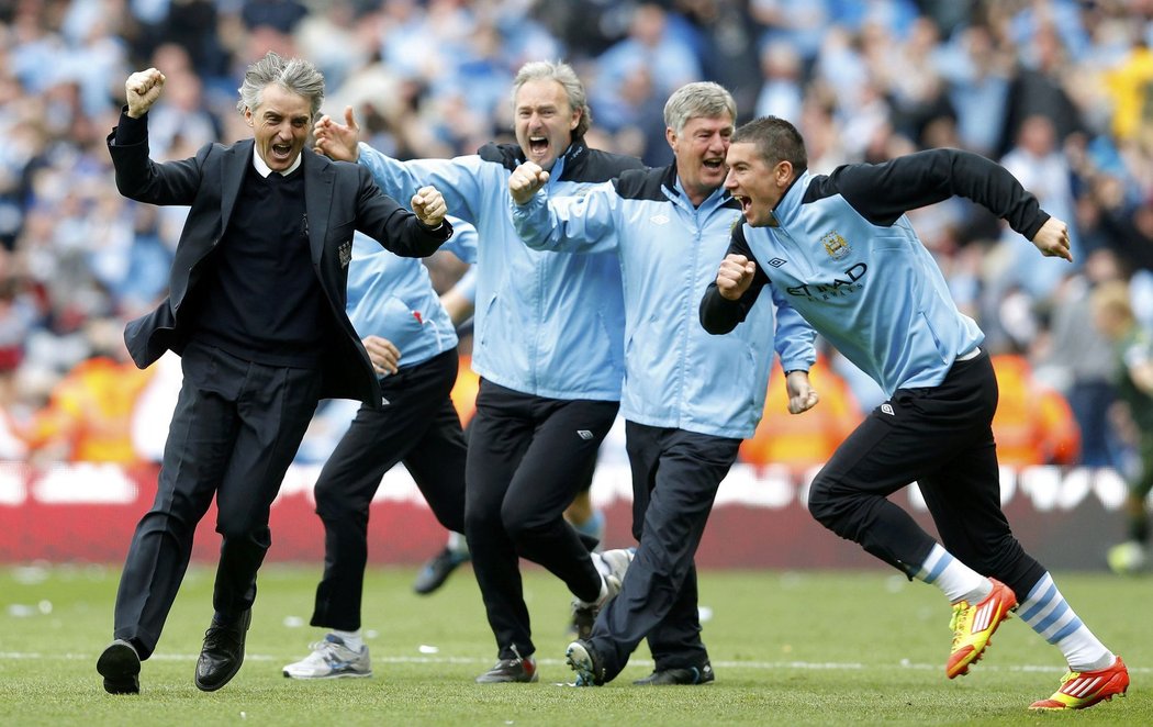 Kouč Manchesteru City Roberto Mancini (vlevo) vbíhá na trávník slavit mistrovský titul, který jeho tým zachránil dvěma brankami v nastaveném čase