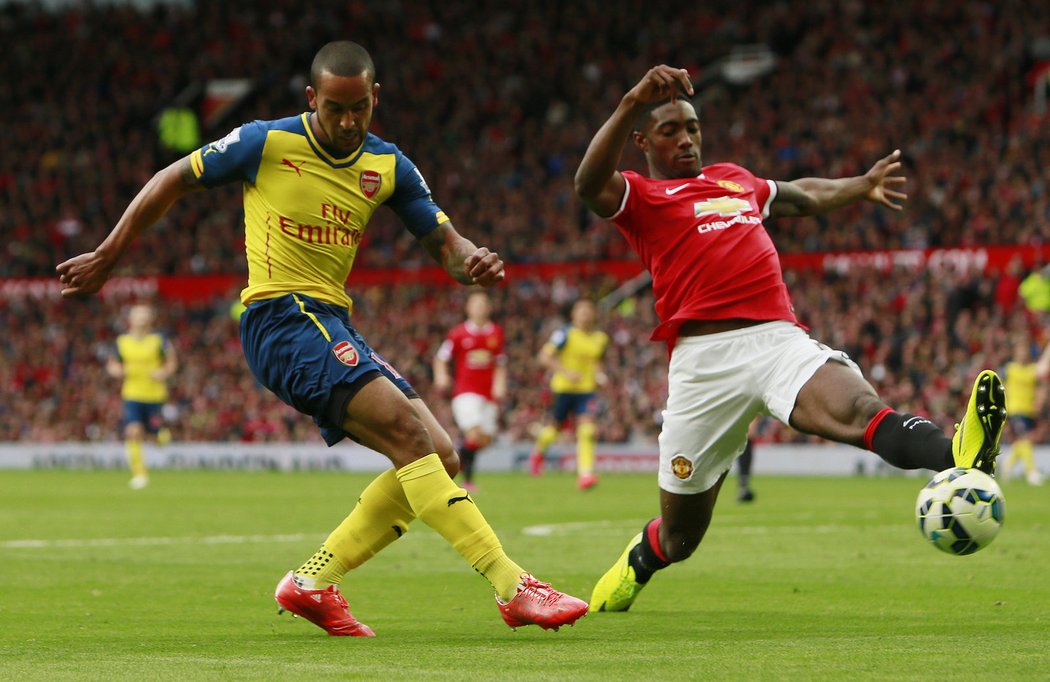 Theo Walcott z Arsenalu posílal míč před branku, jenže centr nešťastně usměrnil do sítě United bránící Tyler Blackett (v červeném). Zápas pak skončil 1:1.