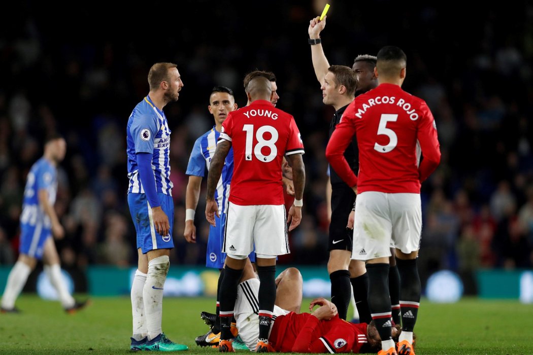 Sudí uděluje žlutou kartu v utkání Manchesteru United s Brightonem