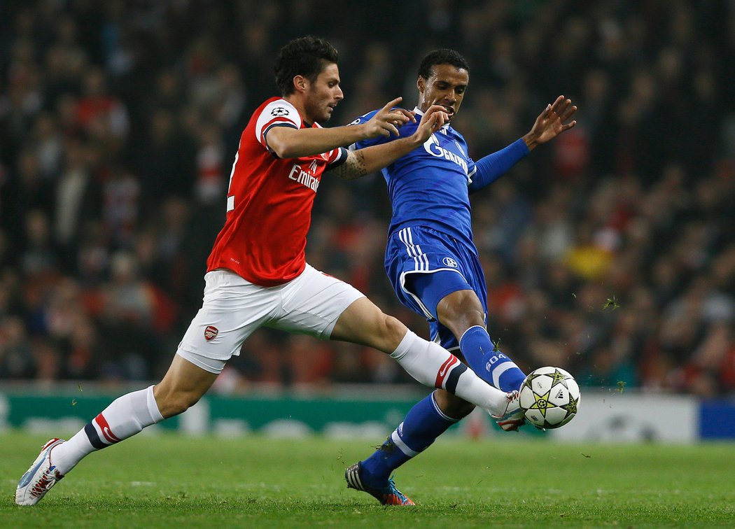 Oliver Giroud z Arsenalu bojuje o míč s Marco Hoegerem v utkání proti Schalke 04