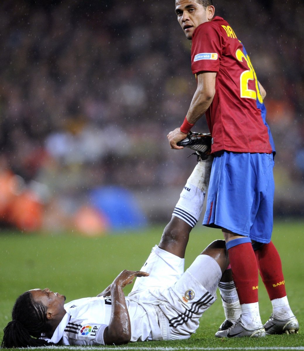 Barcelonský Daniel Alves pomáhá Ricky Drenthemu z Realu Madrid od křeče.